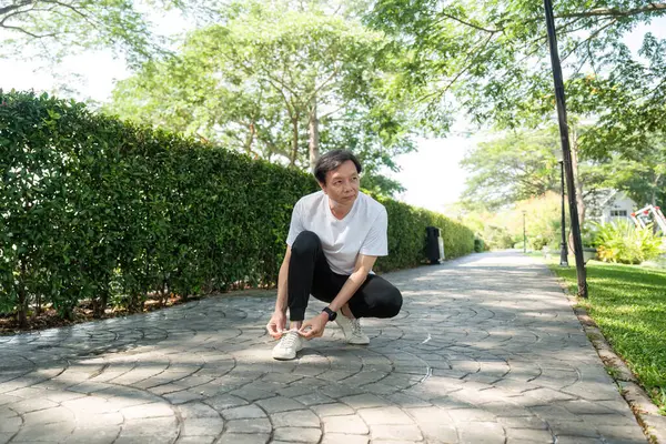 Yaşlı bir adam, sağlık ve zindelik takibini vurgulamak için parkta akıllı saatini kontrol eder..