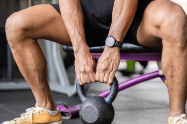Odaklanmış bir birey bir su ısıtıcısını kavrıyor, güçlü bir antrenman oturumuna hazırlanıyor, fitness ve adanmışlığı vurguluyor..