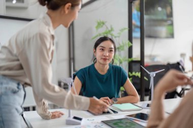 Bir ekip ESG girişimlerini tartışıyor, sürdürülebilir uygulamaları ve işbirlikçi karar verme mekanizmalarını vurguluyor.