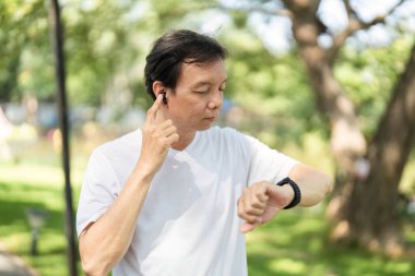 Üst düzey bir adam, açık havada müzik dinlerken, sağlığın ve teknolojinin günlük hayattaki karışımını vurguluyor..