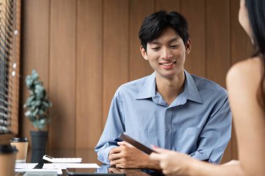 İki meslektaş, çağdaş bir çalışma alanında dijital tabletlerle ilgili finansal verileri analiz ederek bir iş görüşmesine giriştiler..