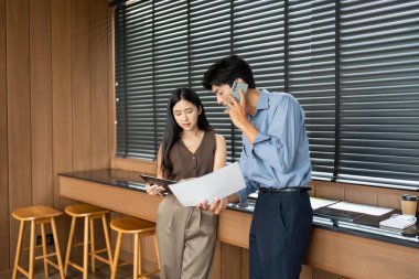 Bir iş kadını ve işadamı proje belgelerini birlikte analiz ediyor, modern bir çalışma alanında takım çalışması ve işbirliği sergiliyor.