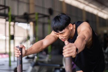 Kararlı bir adam spor salonunda kızak itme egzersizi yapıyor, fitness ve güç kondisyonunu ön plana çıkarıyor..
