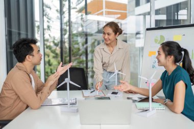 Çeşitli bir ekip ESG stratejileri ve sürdürülebilir uygulamaları tartışıyor, modern ofis ortamında veri sergiliyor.