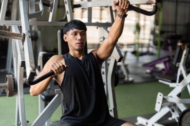 Genç bir erkek sporcu spor aletleri üzerinde kararlılıkla egzersiz yapıyor, güç ve forma odaklanıyor..