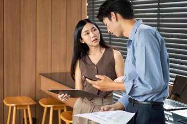 Bir iş kadını ve işadamı, çağdaş bir ofis ortamında strateji ve sezgilere odaklanarak veri raporlarını birlikte analiz ederler..