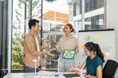 Bir grup profesyonel, sürdürülebilirlik ve ESG hedeflerine olan bağlılıklarını vurgulayan, çevre dostu iş stratejileri hakkında bir tartışmaya girişiyor.