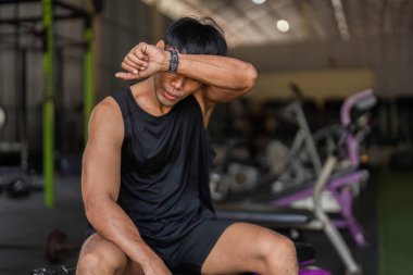 Bir çaydanlık çanı egzersizinden sonra ara veren genç bir adam sağlık ve spor yolculuğunu düşünüyor..