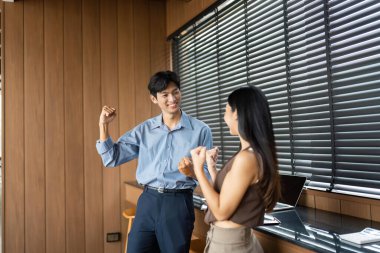 İki genç profesyonel aynı mutlu anı paylaşıyor, başarılarını kutluyor ve şık bir çalışma alanında pozitif bir takım ruhunu teşvik ediyorlar..