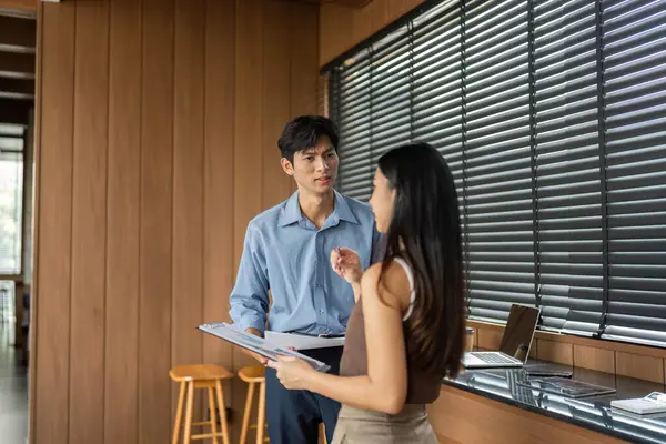 Bir işadamı ve iş kadını, çağdaş bir ofis ortamında proje detayları üzerinde işbirliği yaparak bir tartışmaya giriştiler..