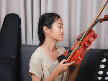 İki genç kız bir kanepede oturuyor, biri keman çalıyor. Diğer kız kemana dokunuyor, muhtemelen arkadaşına yardım ediyor. Arkadaşlık ve destek kavramı