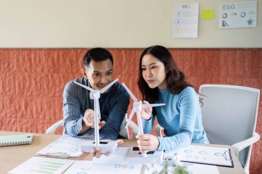 Profesyoneller bir ESG planlama oturumunda, yenilenebilir enerji girişimlerini tartışmak için rüzgar türbini modellerini kullandılar.