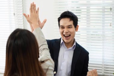 Meslektaşları başarılı bir projeyi kutlarken neşeli bir an. Parlak ofis ortamında beşlik çakarak..