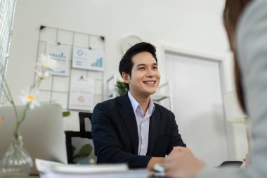 Bir iş danışmanı gülümsüyor ve bir müşteriyle sohbet ediyor, dostane ve profesyonel bir atmosferi teşvik ediyor..