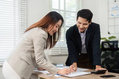 Proje belgeleri üzerinde işbirliği yapan iş adamları, parlak bir ofis alanında stratejiler yazıp tartışıyorlar..