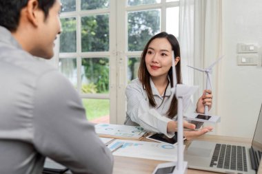 Profesyonellerin yenilenebilir enerji modelleri ve veri görselleştirmeleri ile ESG stratejilerini tartıştığı dinamik bir iş toplantısı.