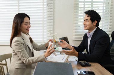 Finansal planlar hakkında verimli bir tartışmaya giren bir kadın ve bir erkek modern ofis ortamında takım çalışması sergiliyorlar..