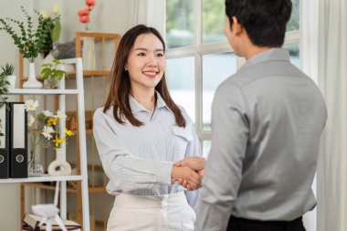 Bir iş kadını, başarılı bir ortaklığı simgeleyen iş arkadaşıyla tokalaşırken gülümser..