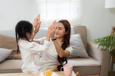 Neşeli bir etkileşimde, bir anne kızıyla yakınlaşır, birlikte okula hazırlanırken neşeli bir ortam oluşturur..