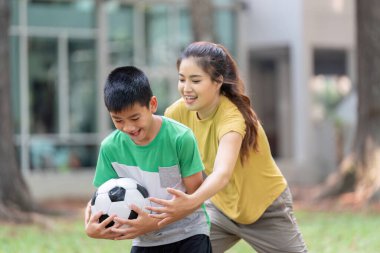 Genç bir kız ve erkek, güneşli bir park ortamında eğlenirken bir futbol topunu ele geçirmek için yarışırlar..