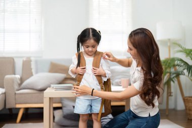 Bir anne, kızının sırt çantasını takmasına yardım eder. Destekleyici ilişkilerini ve yeni bir öğretim yılının neşesini yansıtır..