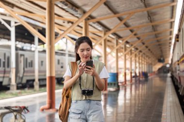 Canlı bir tren istasyonunda, genç bir kadın akıllı telefonunu yerel çekimleri keşfetmek için kullanır. Yolculuğuna hazırlanırken teknolojiyi seyahatle harmanlar..