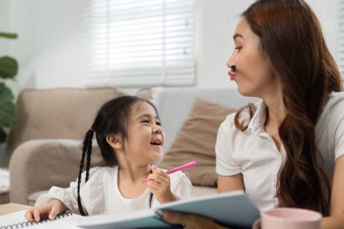 Ödevin ortasında, bir anne ve kızın gülücükler ve kahkahalar atarak ev ortamında birlikte öğrenmenin verdiği keyfi vurguladığı eğlenceli bir an yaşanıyor..