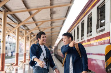 Animasyon ifadeleriyle, iki arkadaş yaklaşan yolculuklarını tartışıyor, tren istasyonunda canlı bir sohbete girişiyorlar..