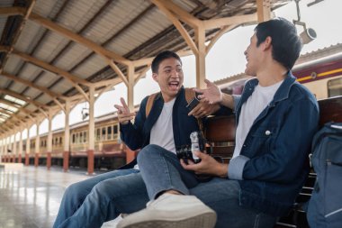 Kahkahalar arasında, iki arkadaş tren istasyonunda mola verirken seyahat planlarını tartışıp gitmeden önce arkadaşlıklarını geliştirdiler..