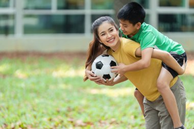 Anne-oğul ikilisi, aktif yaşam tarzlarını ve bir park ortamında bağ kurmalarını vurgulayarak, eğlenceli futbol eğlencelerine girişiyor..