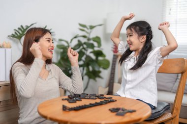 Bir an neşe içinde yakalanan bir anne ve kızı domino oyununu kazandıktan sonra heyecanlarını dile getirirler. İlişkilerinin sıcaklığını ve birlikte vakit geçirmenin mutluluğunu gösterirler..
