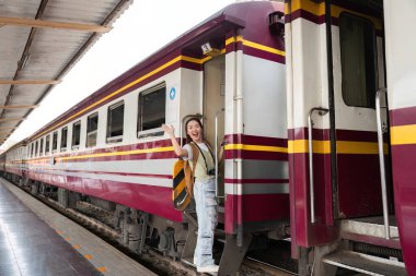 Giderken sevinçle el sallayan genç bir gezgin, tren yolu atmosferinin kucakladığı yolculuğun heyecanını paylaşıyor..