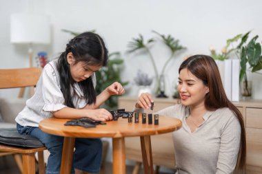 Bir anne kızına lego oyununda akıl hocalığı yaparken, eğlenceli etkileşimler yoluyla öğrenme ve aile bağlarını vurgulayan iç açıcı bir sahne gözler önüne seriliyor..