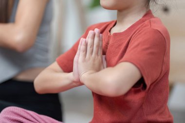 Bir çocuk meditasyon pozisyonunda oturur gözleri kapalı, elleri dua pozisyonunda, derin farkındalığı yansıtır ve sakin ve sakin bir atmosfere odaklanır..