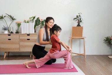 Bir annenin kızına esneme egzersizlerinde yardım ettiği, spor yapmanın önemini eğlenceli bir şekilde vurguladığı bir an..