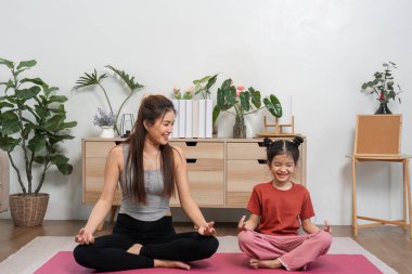 Bir anne ve kızı, meditasyonda huzurlu bir anı paylaşıyor. Bu da kapalı mekan ortamında farkındalığı ve sakinliği cesaretlendiriyor..