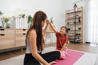 Bir anne ve kızının etkileşimli bir egzersiz yaptığı spor seansı. Spor ve kahkahalarla bağlanma üzerine..