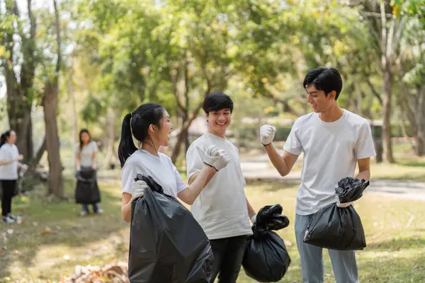 Üç genç gönüllü, çöp topladıktan, sürdürülebilirliği ve takım çalışmasını teşvik ettikten sonra neşeli bir anı paylaşıyor.
