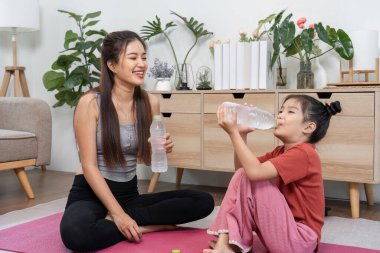 Kısa bir aradan sonra, neşeli bir kız, akıl hocası tarafından sağlanan suyu mutlu bir şekilde içiyor, fitness ve susuz kalma sevincini kutluyor..