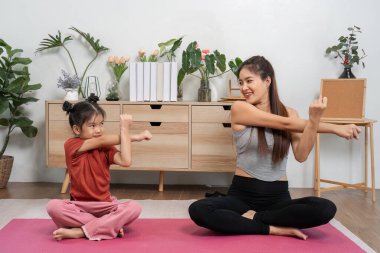 Bir anne ve kızı eğlenceli ısınma hareketleri yapar, fiziksel konforu ve bağlantıyı teşvik eder, ev ortamının keyfini çıkarırlar..