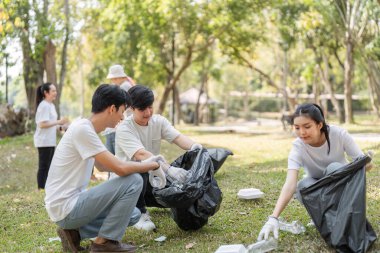 Çeşitli gönüllülerden oluşan bir grup, sürdürülebilirlik ve kamu hizmetine olan bağlılıklarını sergilemek için parkta çöp topluyor..