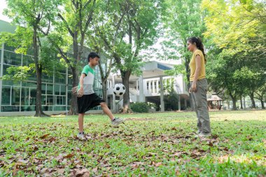 Çocuk, annesi onu cesaretlendirirken futbol topuyla hokkabazlık yapıyor ve doğadaki faaliyetleri sırasında aile bağlarını güçlendiriyor..