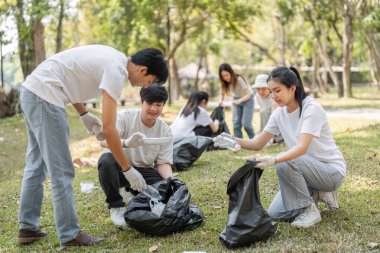 Genç gönüllüler parkta birlikte çalışıyorlar, çöpleri topluyorlar ve çevresel sorumluluk yoluyla toplum bilincini destekliyorlar..