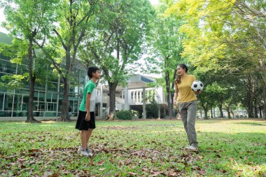 Bir erkek ve bir kadın, parkta birlikte futbol oynayarak keyifli bir anı paylaşıyorlar. Oyun ve takım çalışmasıyla bağlarını güçlendiriyorlar..