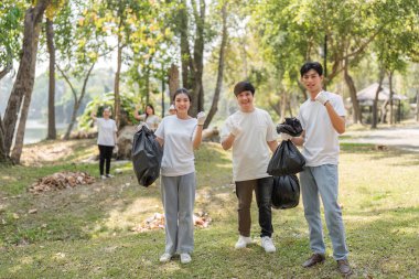 Bir grup hevesli gönüllü, çöp torbalarını tutarken gülümsüyor ve çevresel sürdürülebilirliğe bağlılıklarını sergiliyorlar..