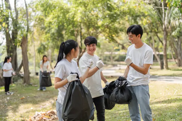 Üç genç gönüllü parkta başarılı bir sedye koleksiyonundan sonra gülümseyip yumruk tokuşturuyorlar..