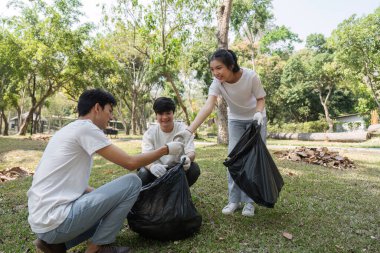 Bir grup gönüllü, atık toplarken dostça sohbete girişerek, sürdürülebilirliğe toplumsal katılımın önemini vurguluyor.
