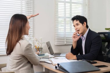 Bir kadın, bir erkeğe finansal kavramları coşkuyla anlatıyor, çağdaş bir ofis ortamında işbirliğini teşvik ediyor..