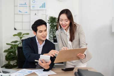 İki iş adamı, mali verileri tartışırken, parlak bir ofiste takım çalışması ve motivasyonu tartışırken başarılarını kutluyorlar..