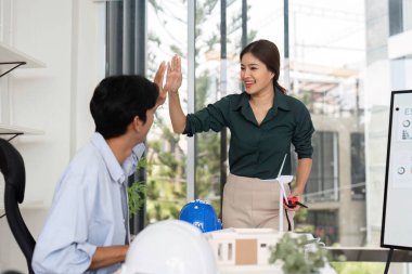 Bir kadın ve bir erkek, yenilenebilir enerji çözümlerinde işbirliği sergileyerek takım çalışmasını kutluyorlar..